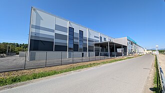 Modernes Industriegebäude von Siemens Energy in Wollsdorf mit grauer Fassadengestaltung, aufgenommen an einer sonnigen Straße