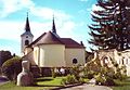 Der Blick auf die Kirche, davor Anni und Hilda in „ihrem“ Rosengarten.