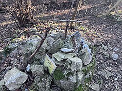 2024 wurde das verbogene Metallkreuz von Unbekannten entfernt und durch ein Holzkreuz ersetzt.